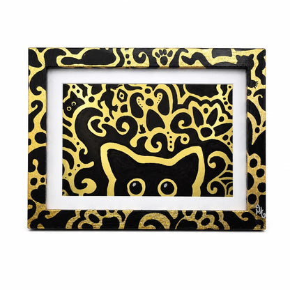 A framed art print featuring a black and gold patterned design with a stylized cat face and abstract swirls, set against a plain white background.