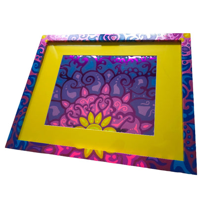 A square decorative picture frame with a bright yellow mat and a colorful psychedelic border, holding a matching mandala art print on a white background.