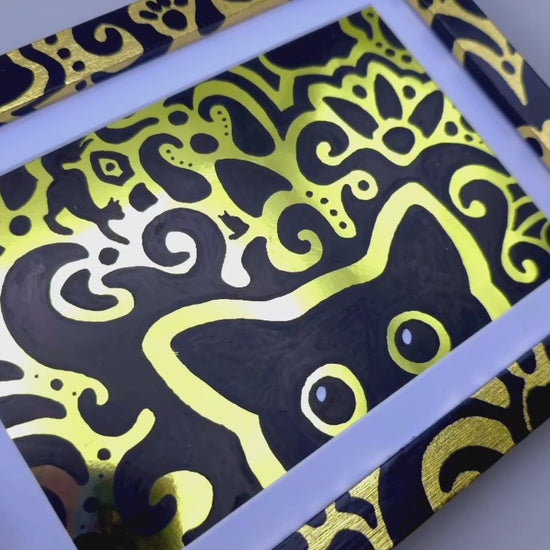 Angled view of the shift supervisor artwork with a gold foil background, gold leaf frame and cat themed