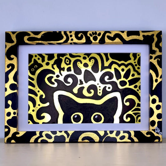 A framed art print featuring a black cat silhouette surrounded by intricate gold and white abstract swirl patterns on a black background, set in a white mat and a black frame with gold cat motifs.